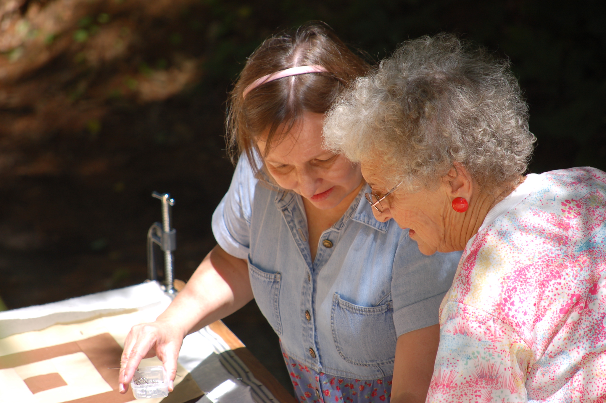 Two women working closely together over a quilt in a hand-quilting frame